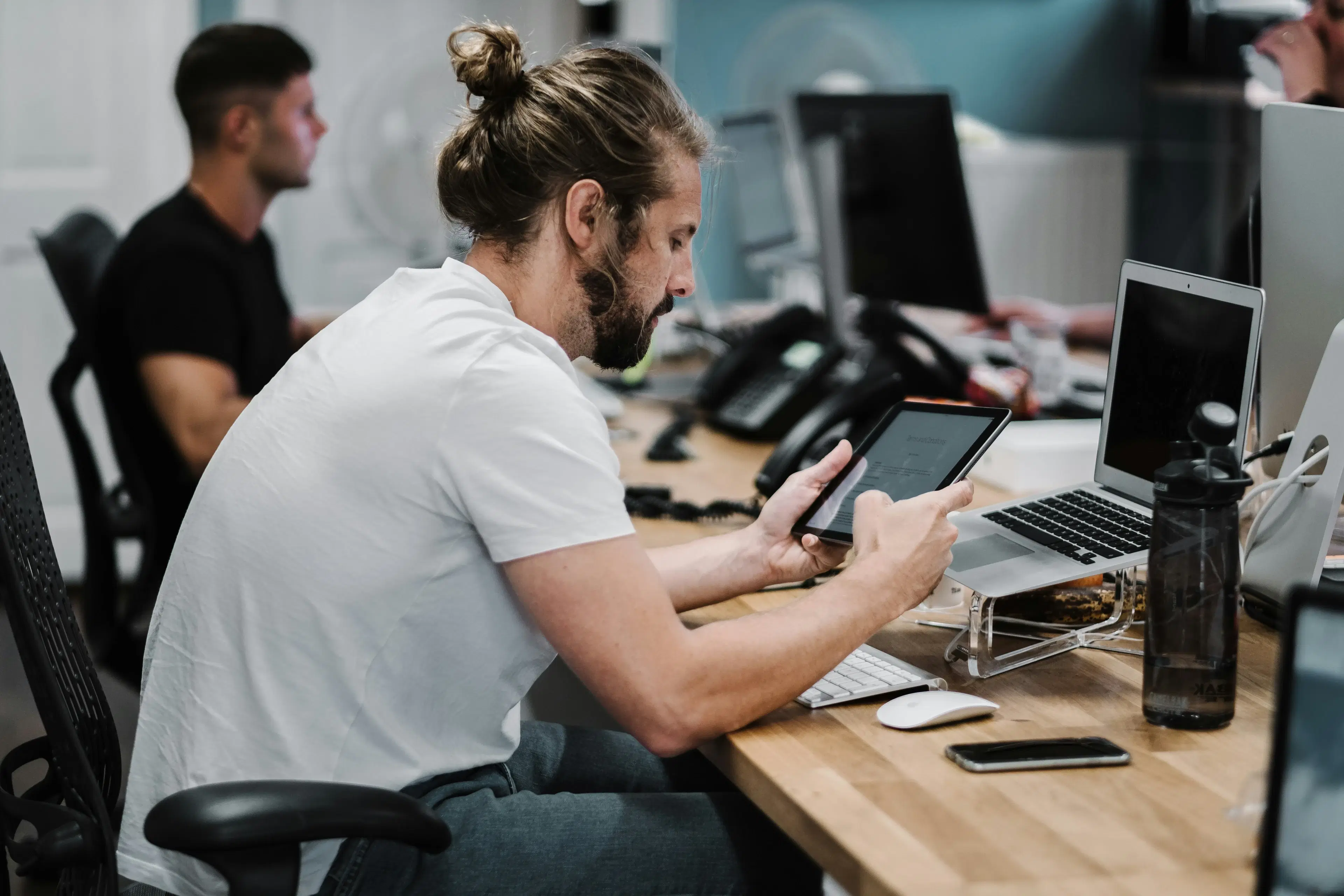 Someone checking a campaign on their phone at a desk with a laptop