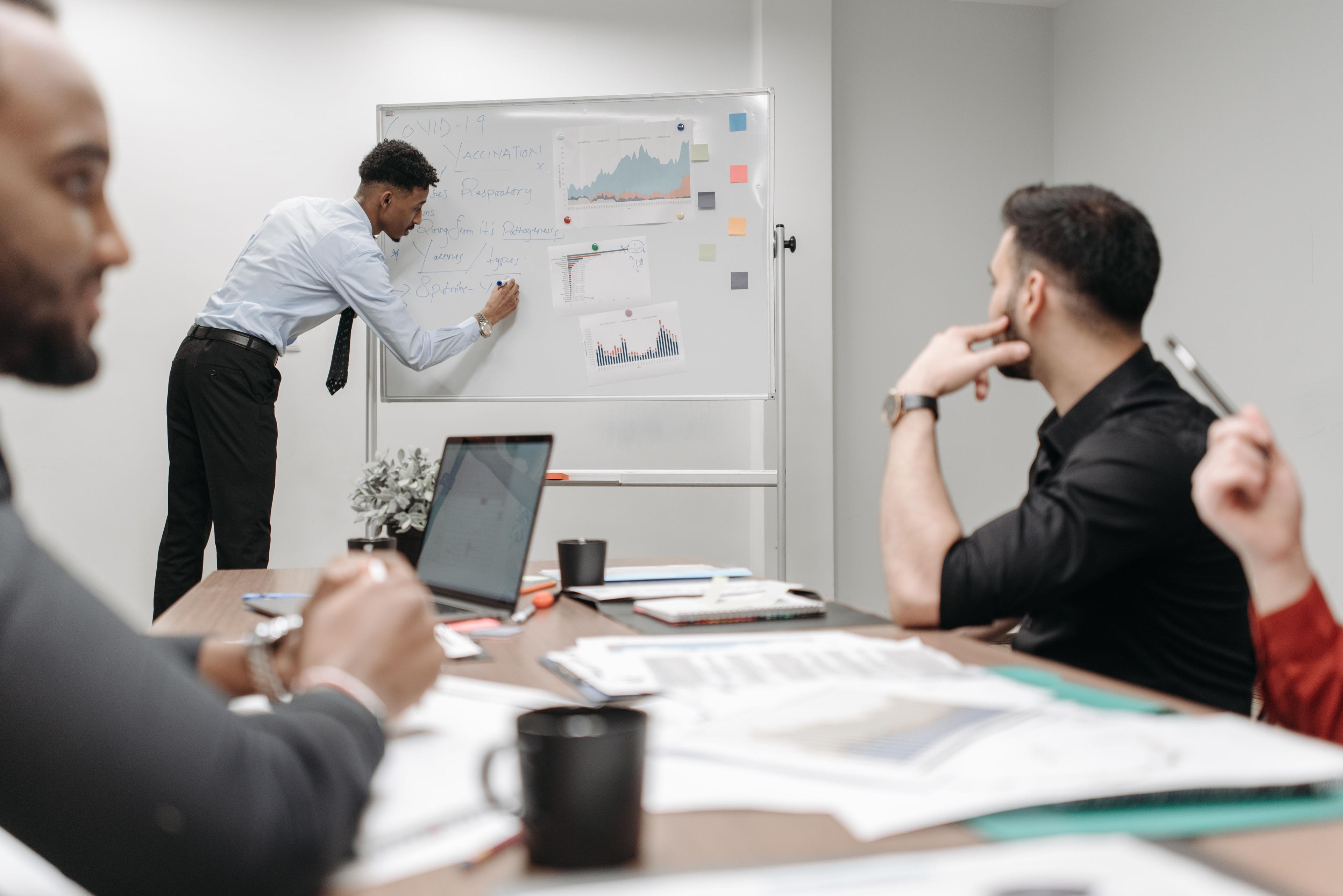 A business analyst facilitating a process mapping workshop at a whiteboard