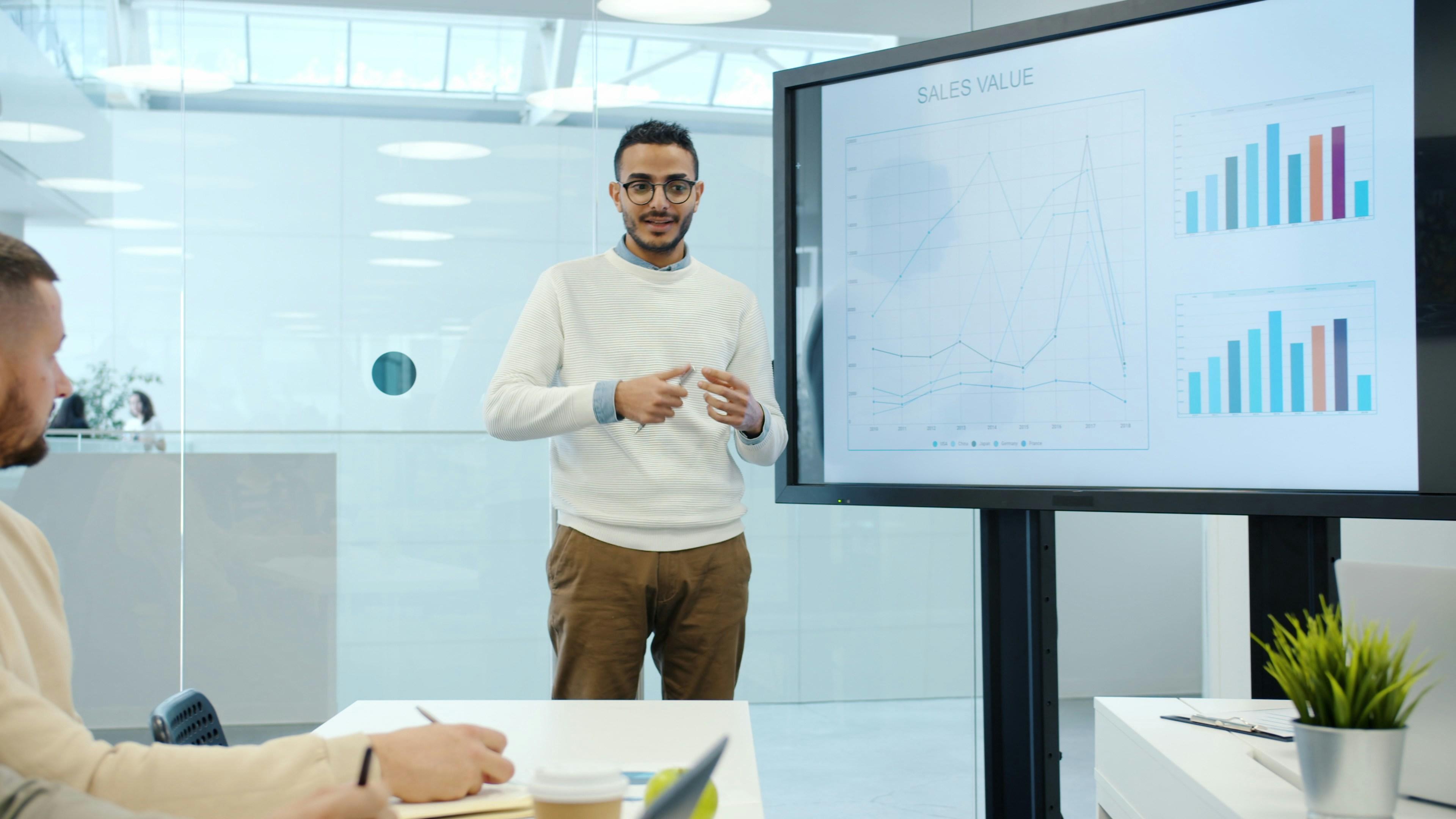 A marketer presenting campaign charts on a screen to colleagues